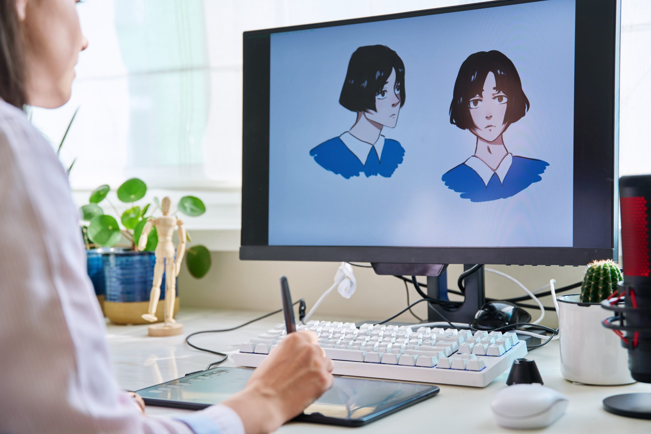 Ilustrador digital trabajando con tableta gráfica en el diseño de personaje estilo anime, mostrado en un monitor de ordenador.